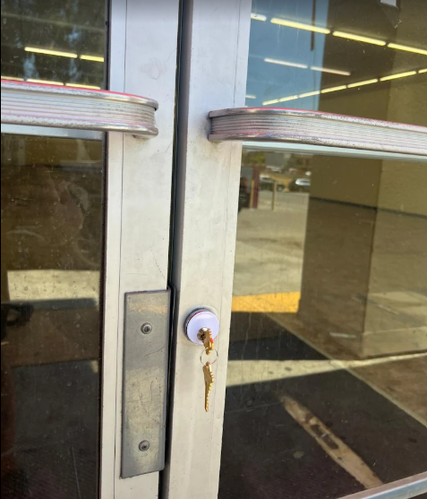 Commercial glass storefront door with key in mortise lock during a business lockout in San Diego